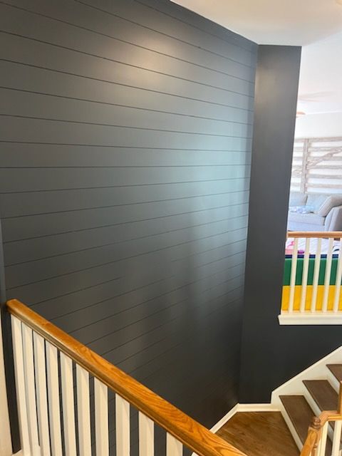 A staircase with a black wall and a white railing