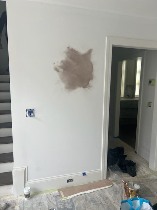 A white wall is being painted in a room with stairs.