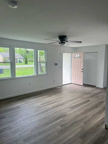 An empty living room with hardwood floors and a ceiling fan.