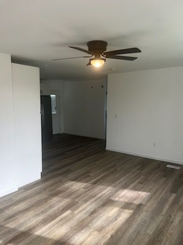 An empty living room with hardwood floors and a ceiling fan.