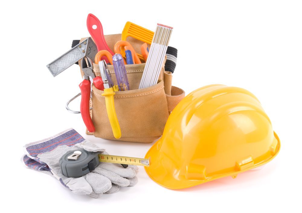 A hard hat is next to a tool belt filled with tools