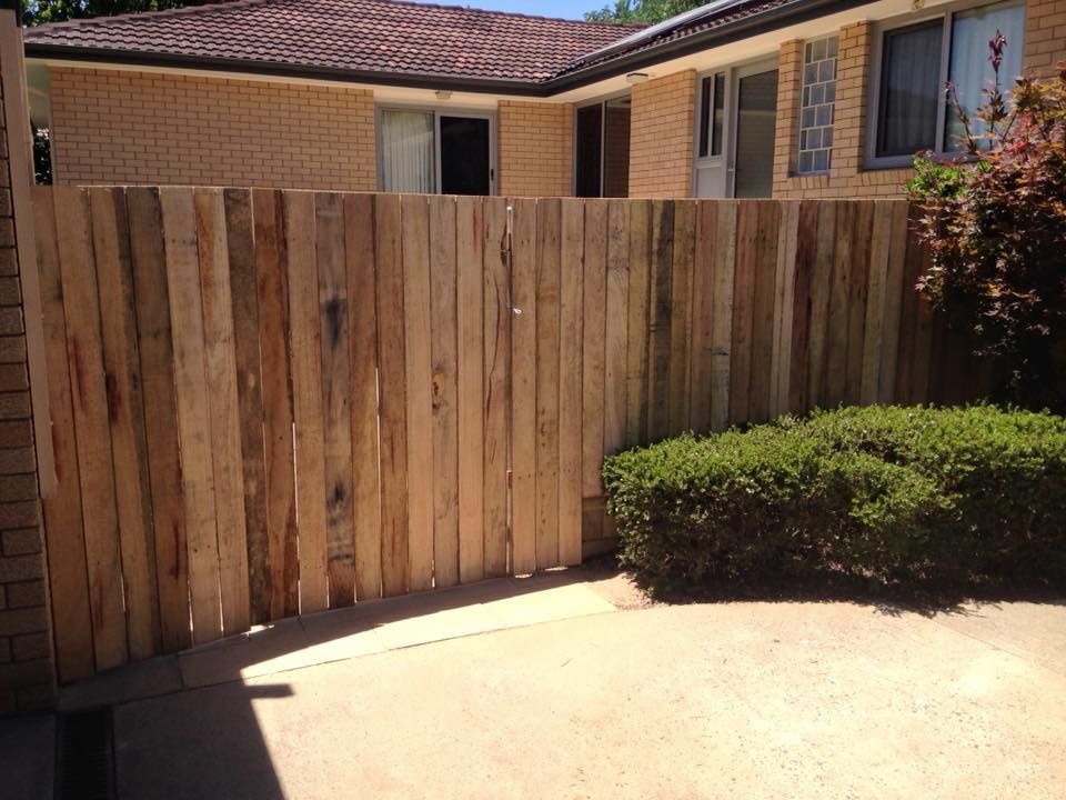 A wooden fence is in front of a brick house.