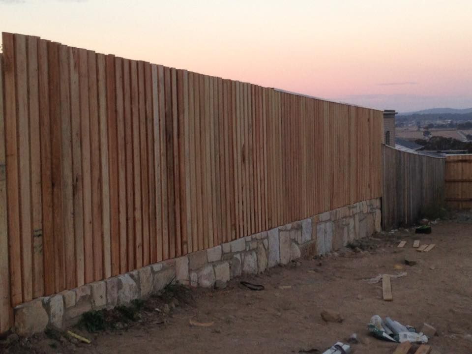 A wooden fence is sitting on top of a stone wall.