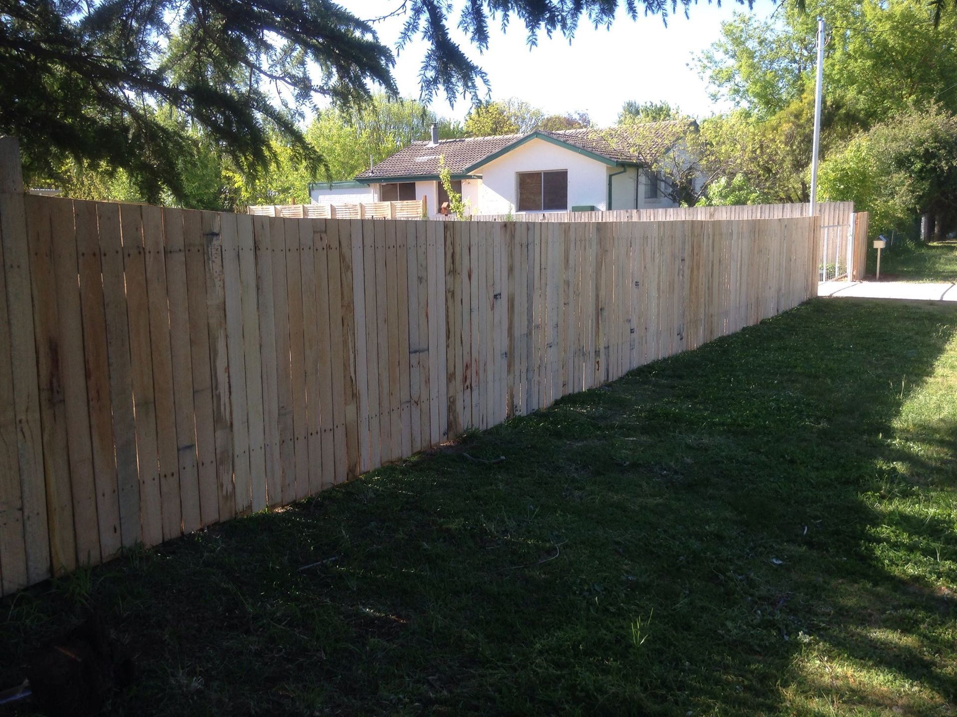 A wooden fence surrounds a lush green yard in front of a house