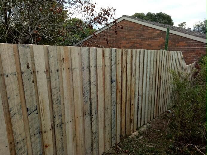 A wooden fence is sitting in front of a brick house.