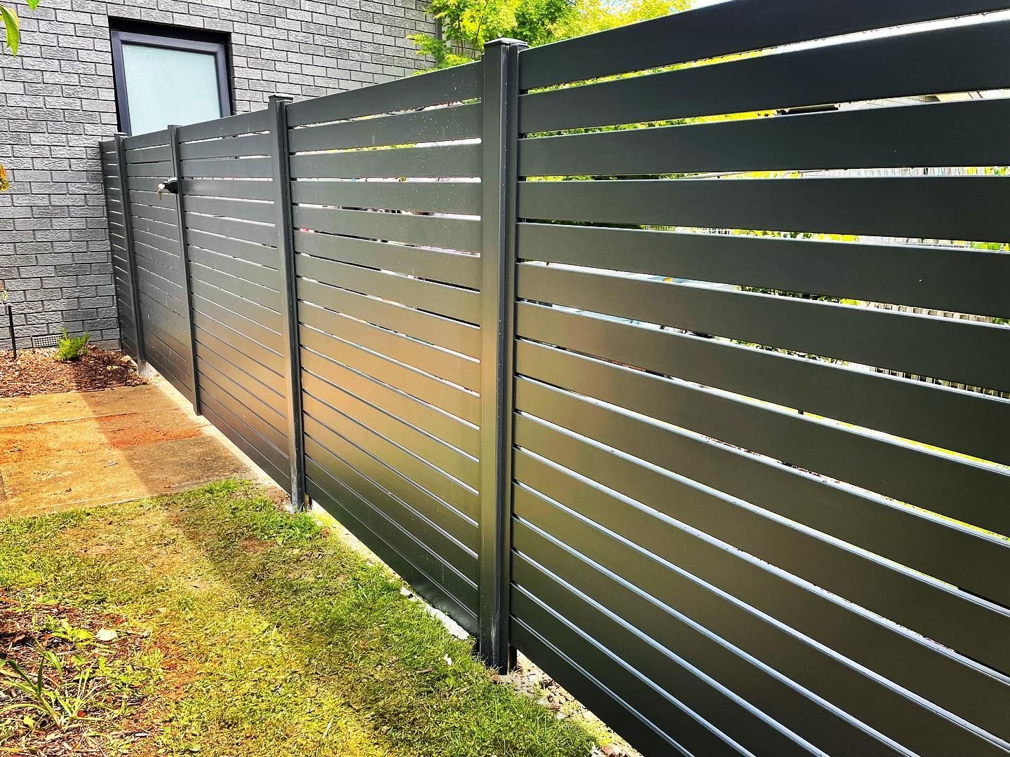 A black fence is sitting in front of a brick building.