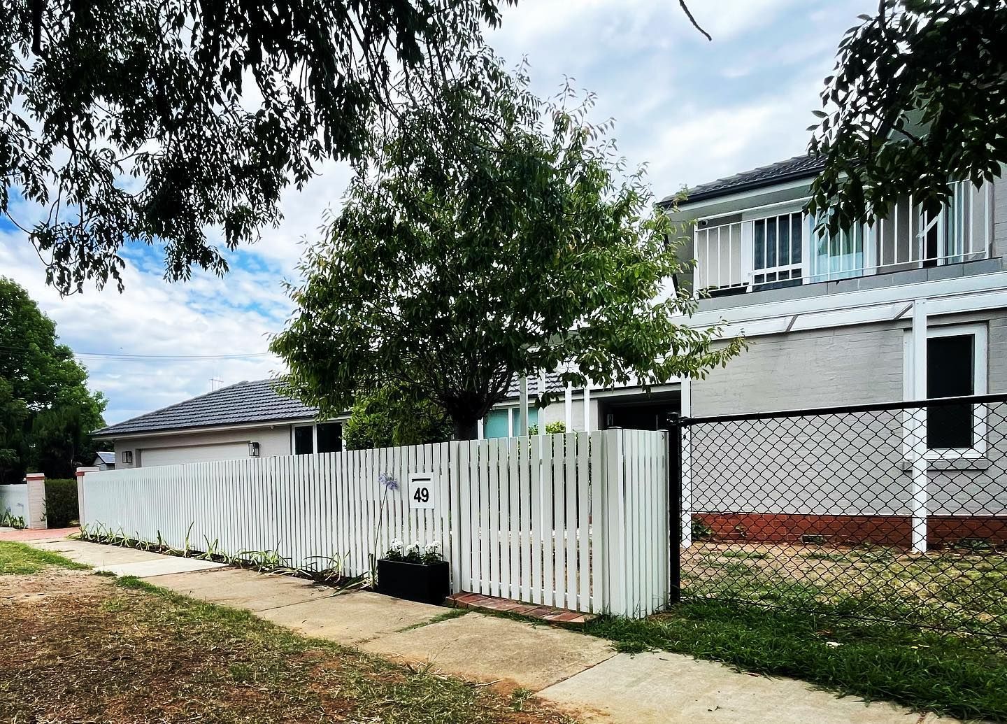 A white fence surrounds a house with the number 41 on it