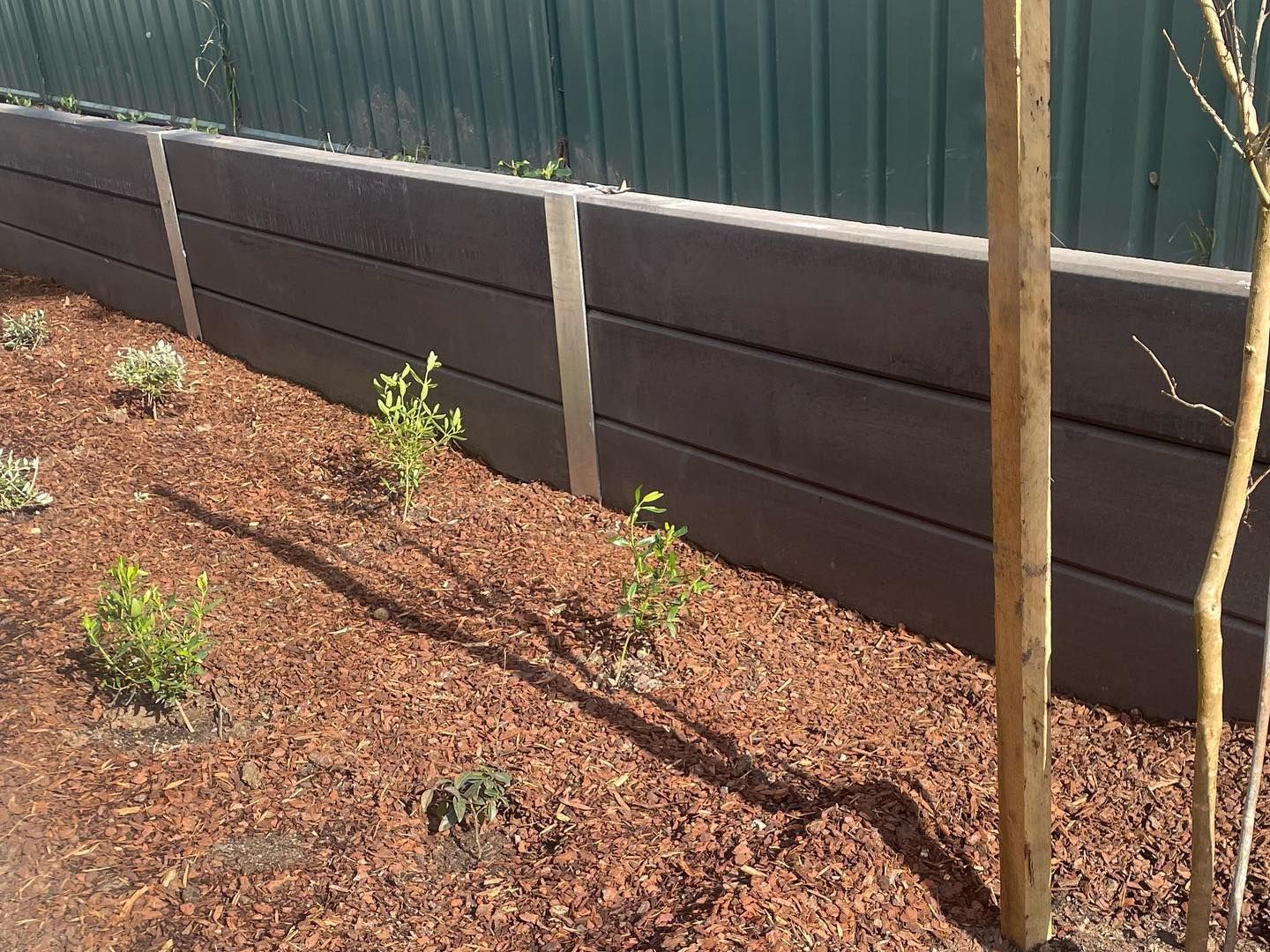 A retaining wall surrounded by a pile of mulch and plants.
