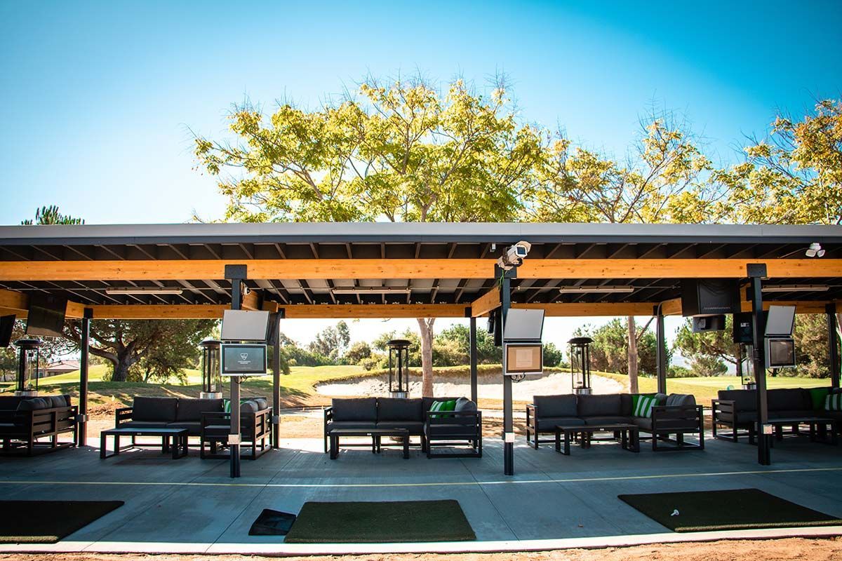A row of benches under a covered area with trees in the background.