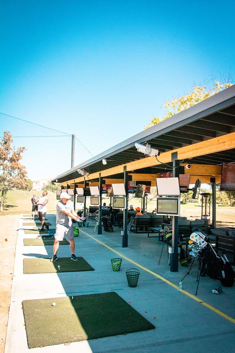 A man is swinging a golf club at a golf course.