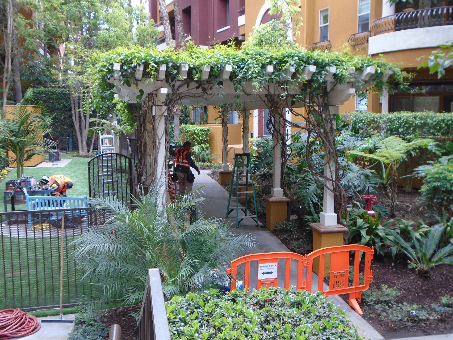 A garden with a pergola and an orange barrier