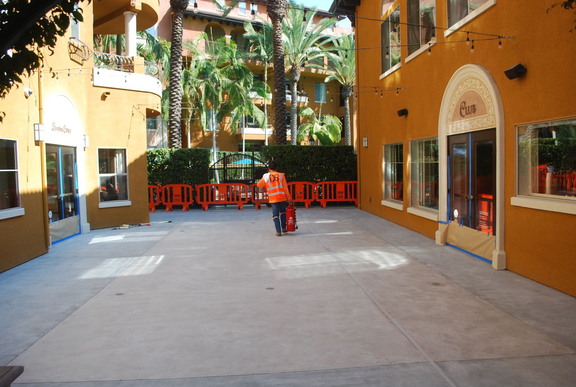 A man in an orange vest is walking in front of a building
