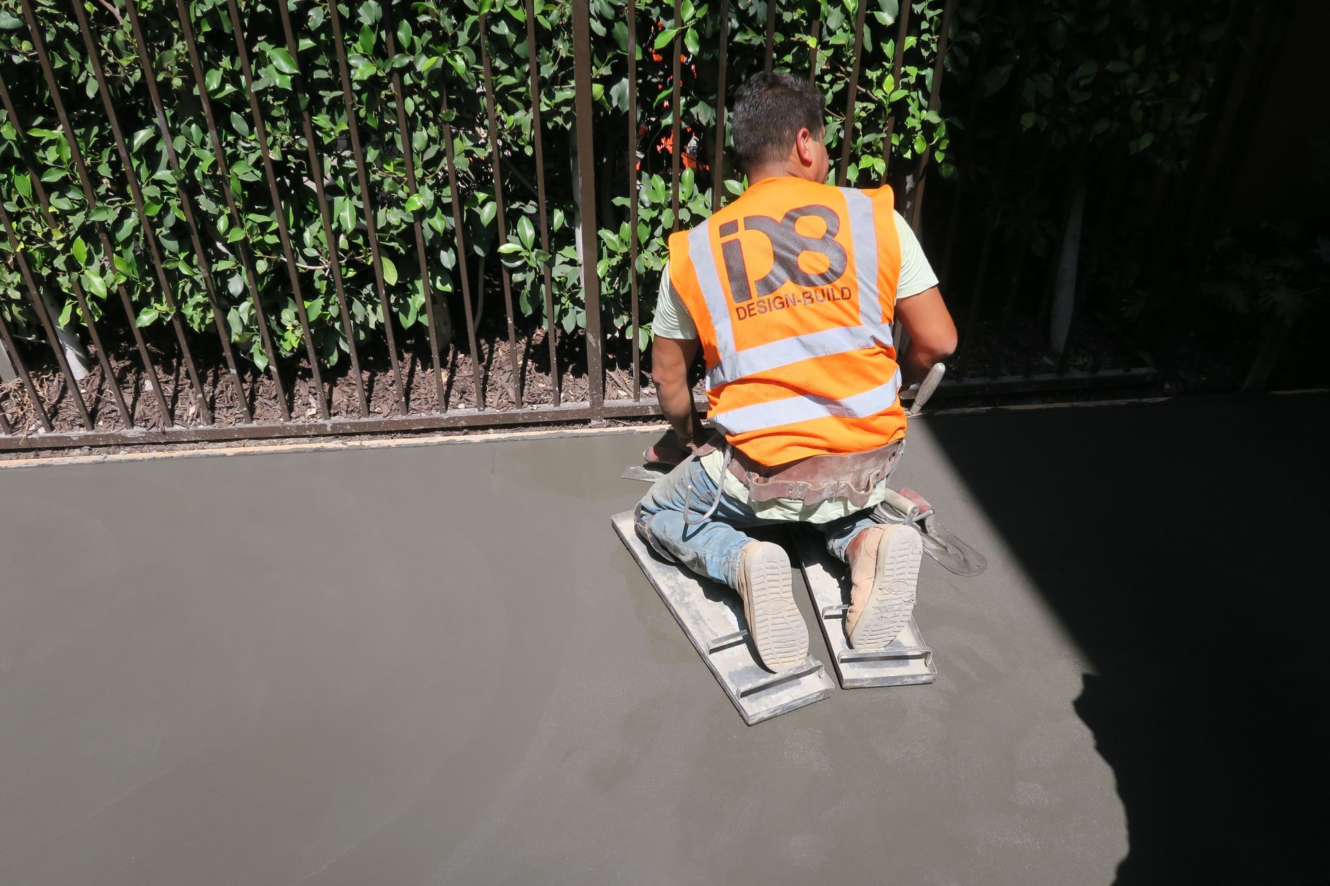 A man wearing an orange vest is kneeling down on the ground.