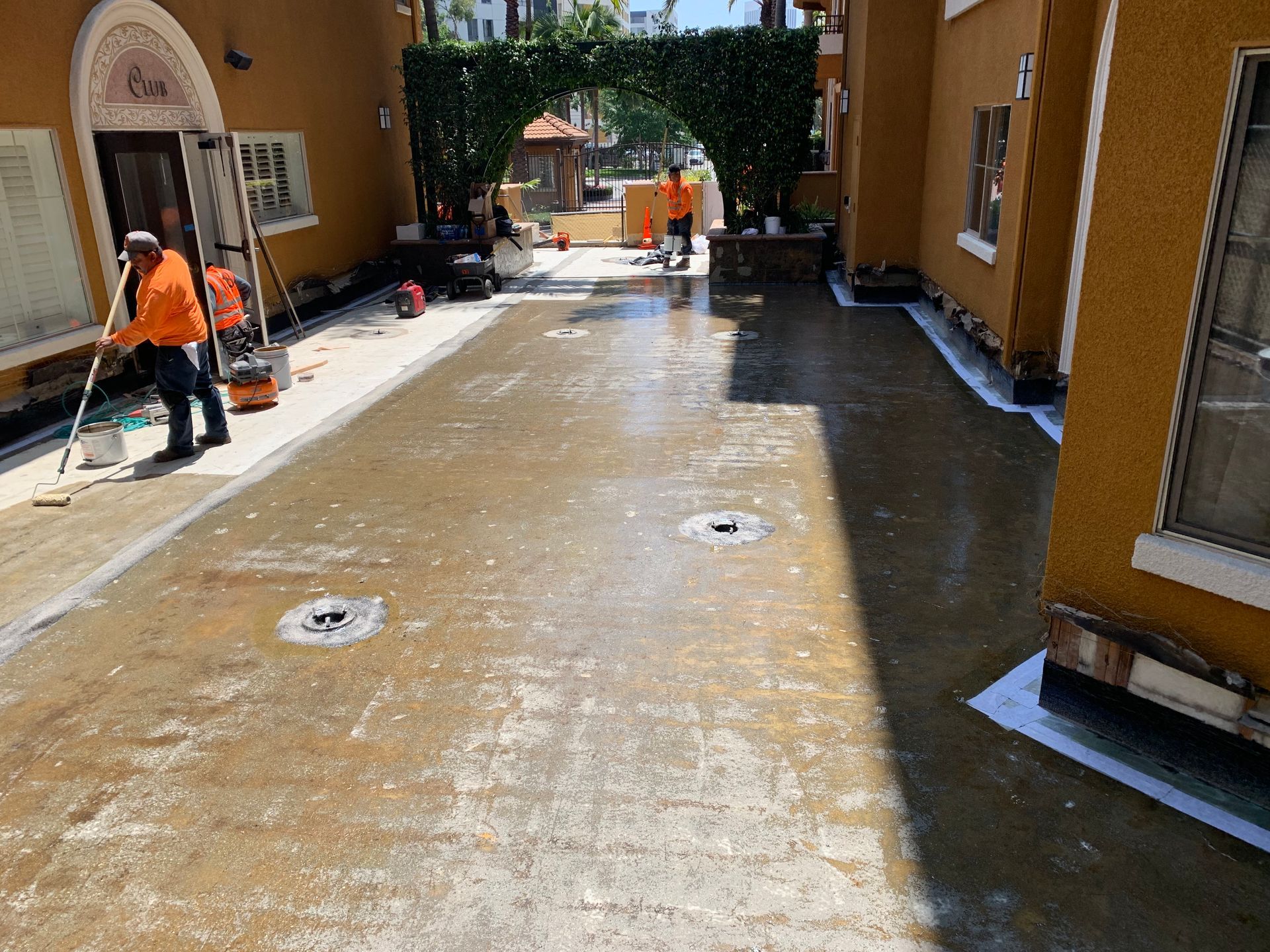 A man is cleaning a concrete driveway in front of a building.
