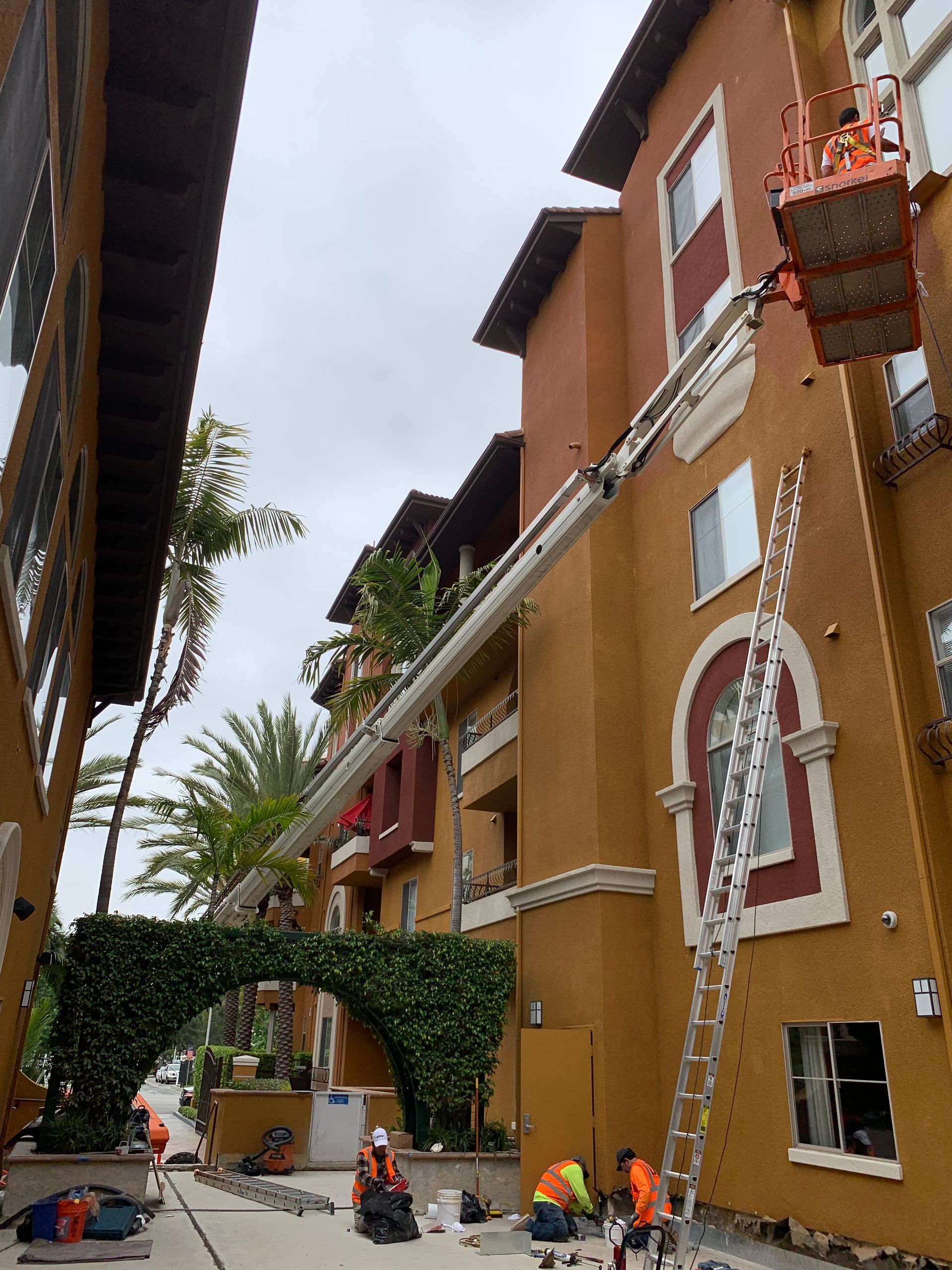 A crane is being used to paint the side of a building.