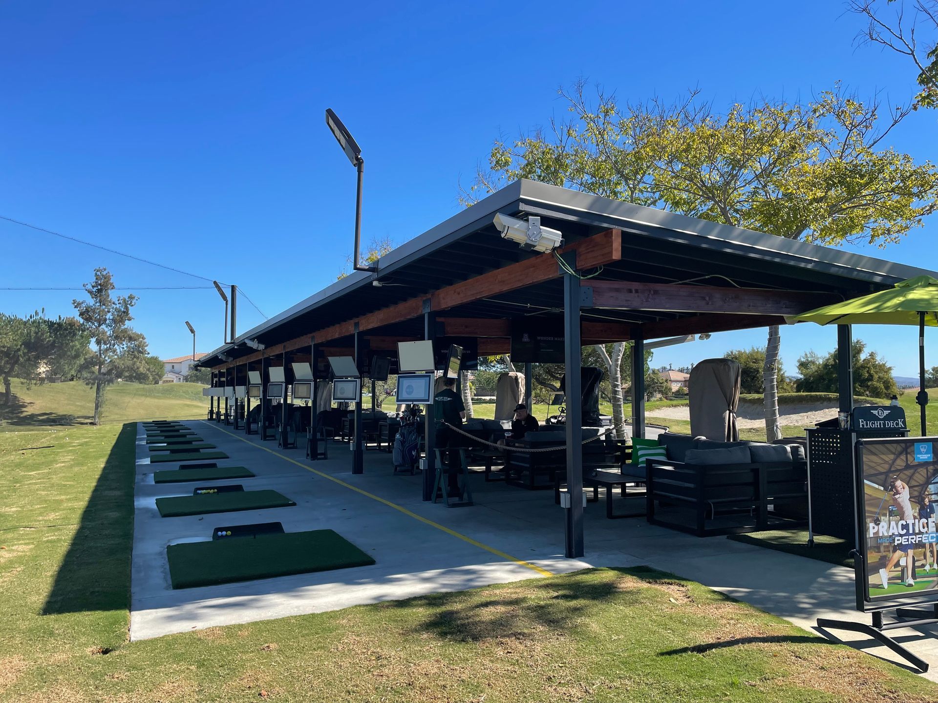 A row of golf balls are lined up on a golf course under a canopy.