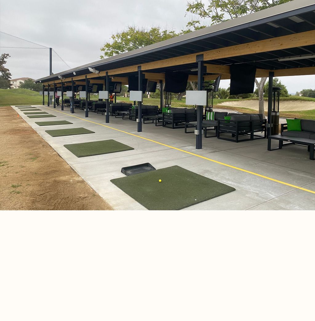 A row of benches under a canopy at a golf course.