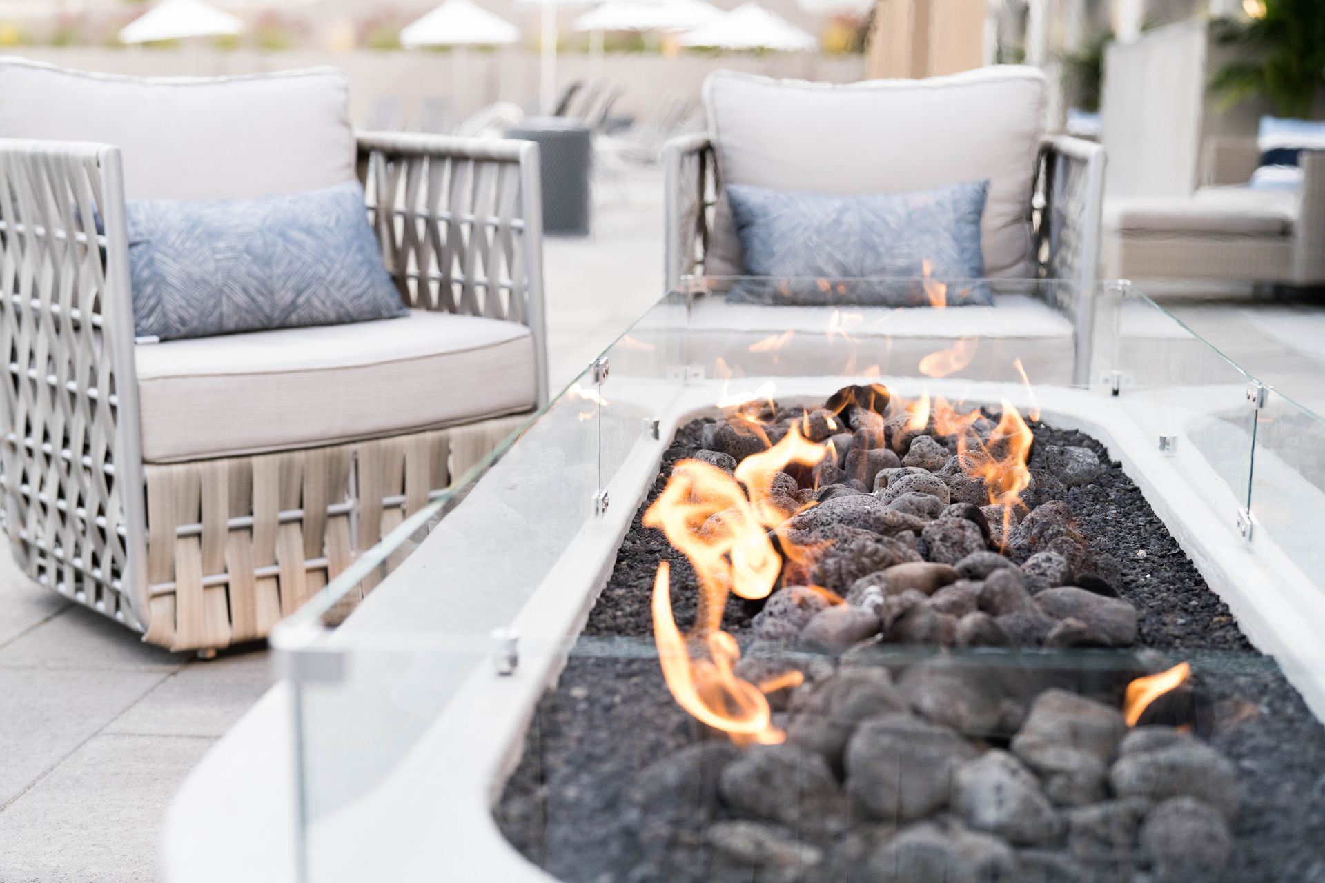 Two chairs are sitting next to a fire pit on a patio.