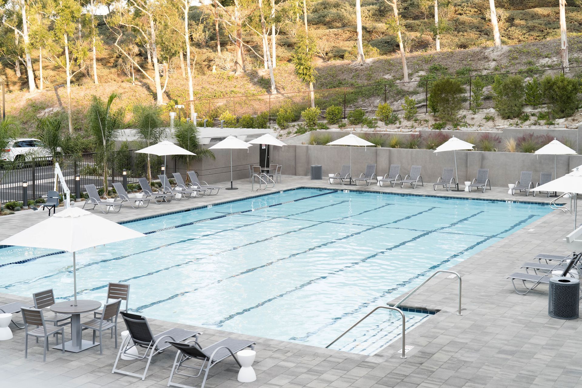 A large swimming pool surrounded by chairs and umbrellas.