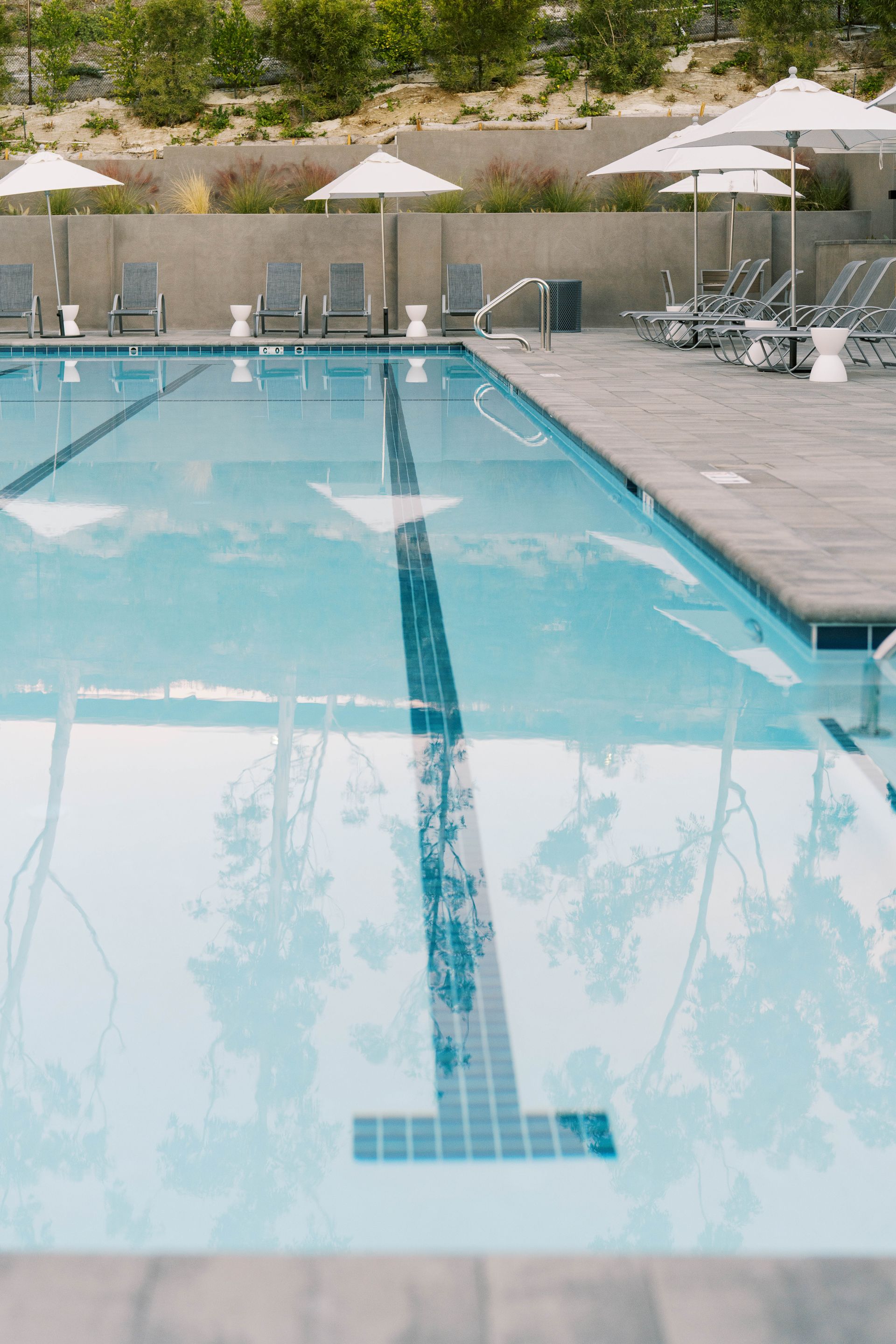 A large swimming pool surrounded by chairs and umbrellas.
