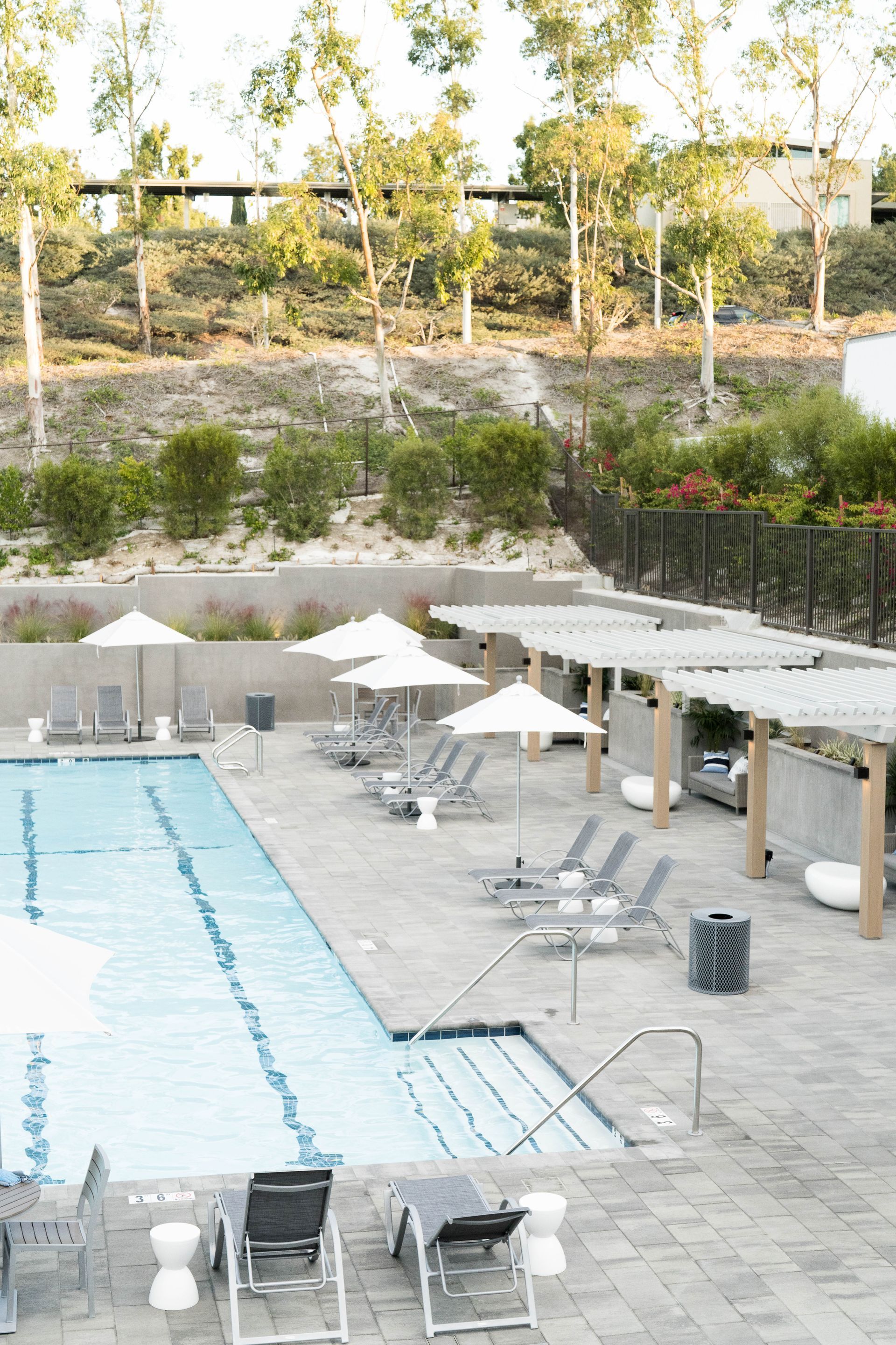 An aerial view of a large swimming pool surrounded by chairs and umbrellas.