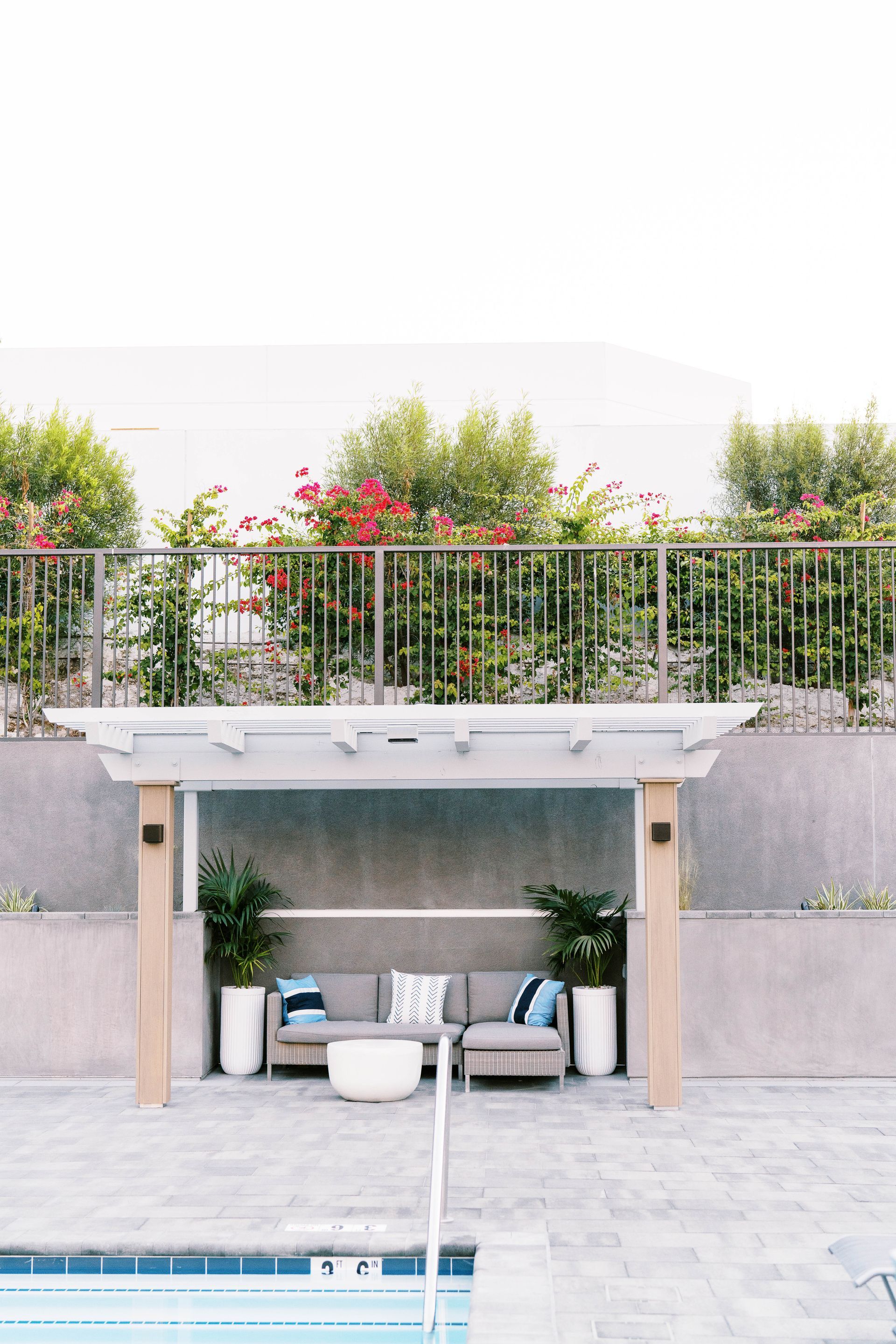 A patio area with a couch and a table next to a swimming pool.