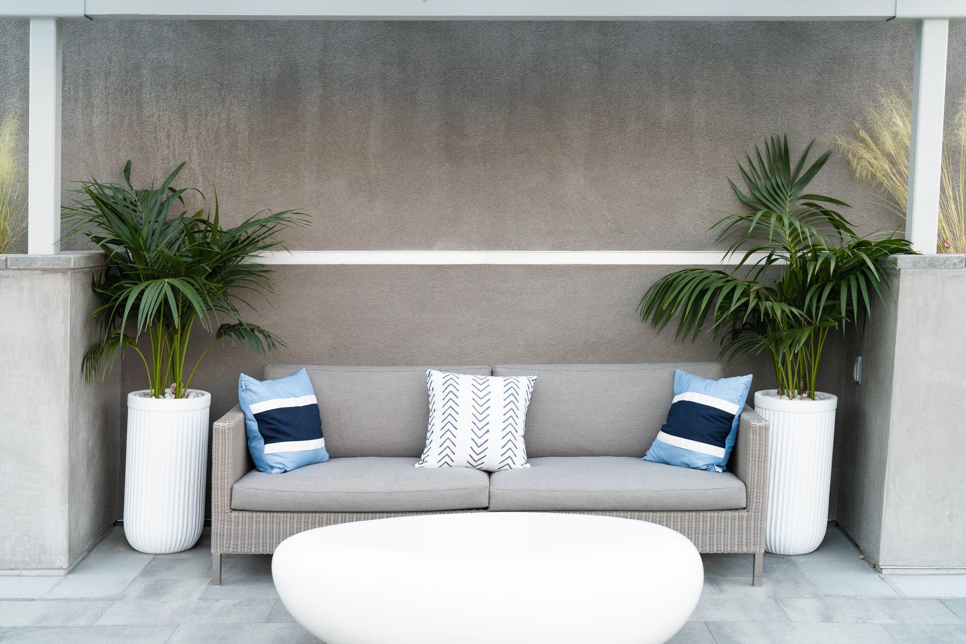 A patio with a couch , table , and potted plants.