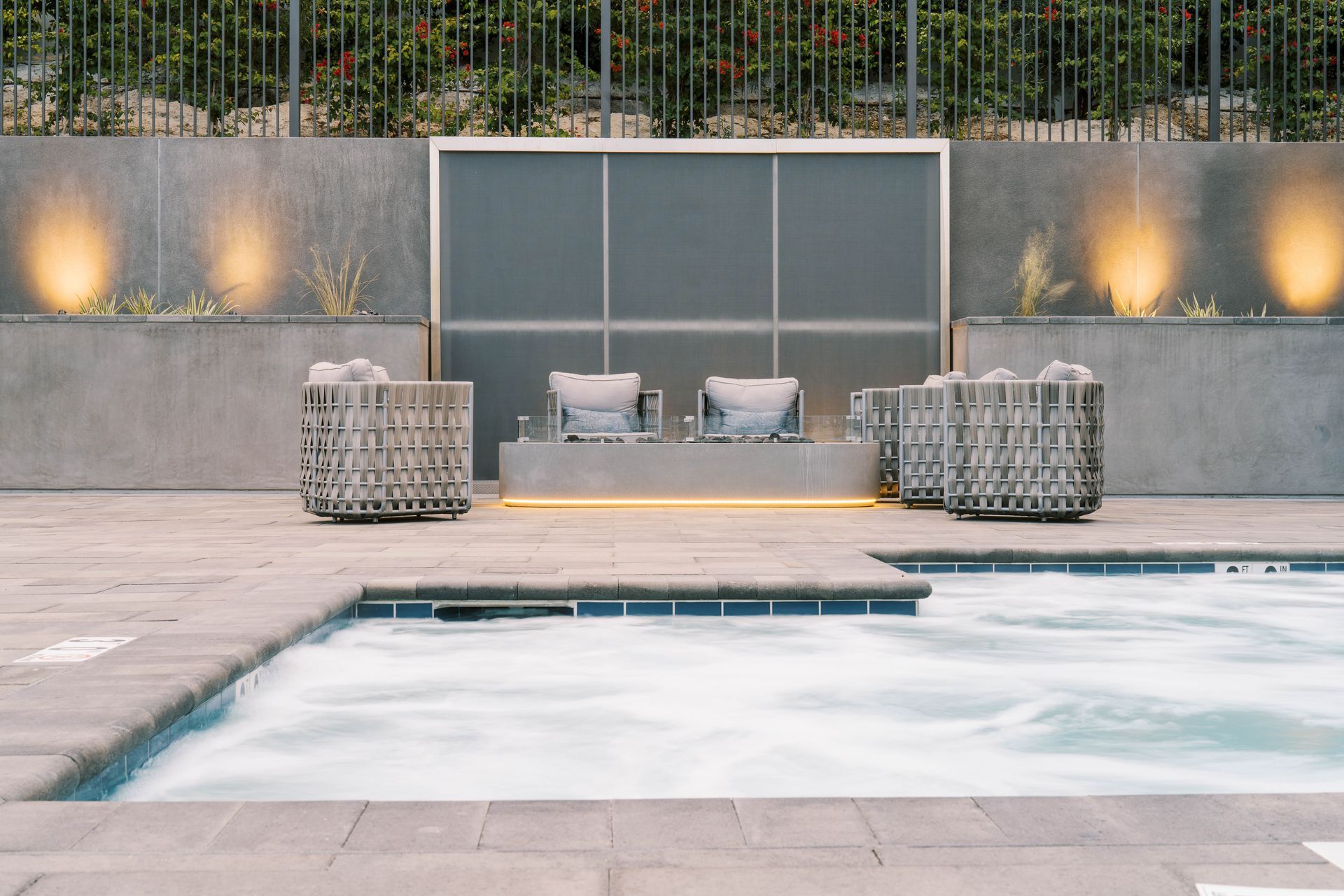 A swimming pool with chairs and a waterfall in the background.