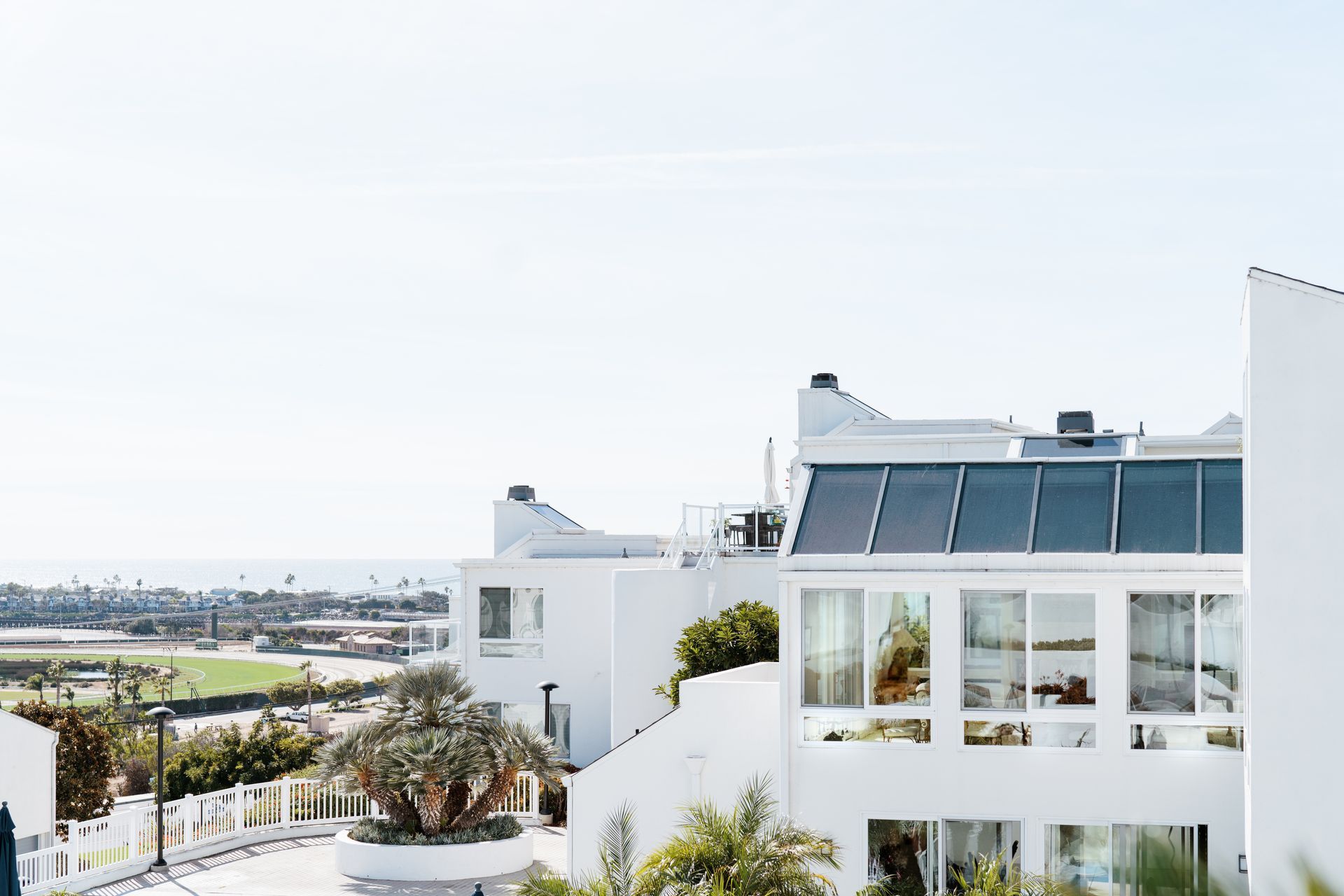 A large white building with a lot of windows is surrounded by trees.