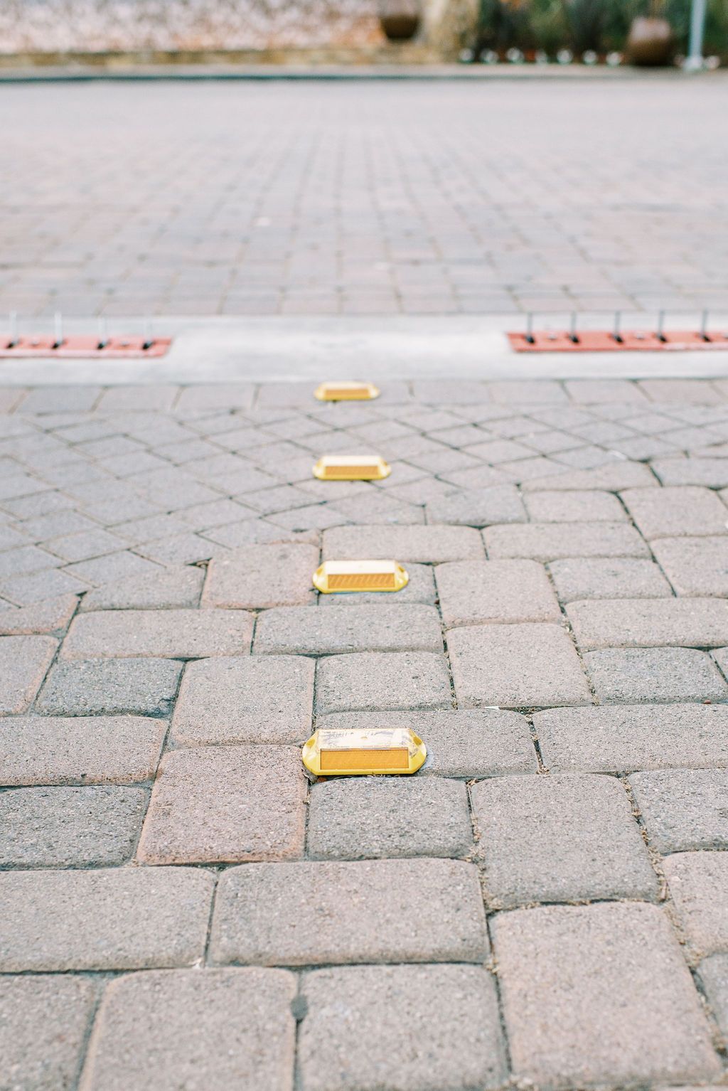A close up of a brick driveway with yellow markers on it.