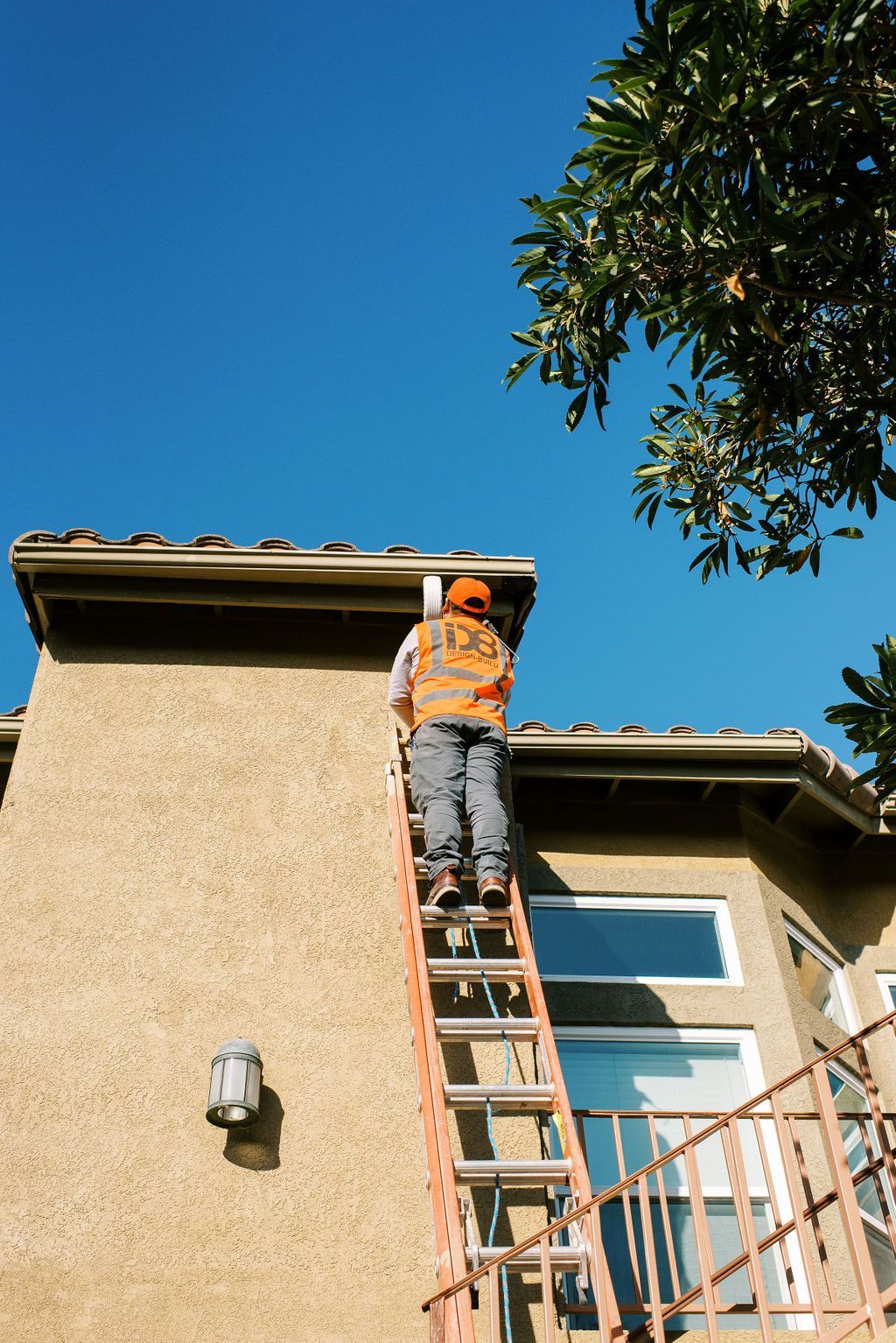 A man is standing on a ladder on the side of a building.