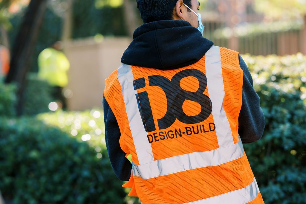 A man wearing an orange vest with the word design-build on it.