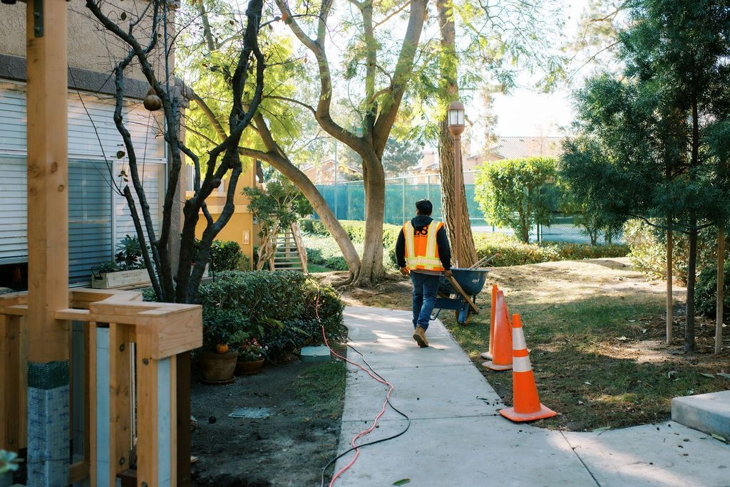 A man in an orange vest is walking down a sidewalk.