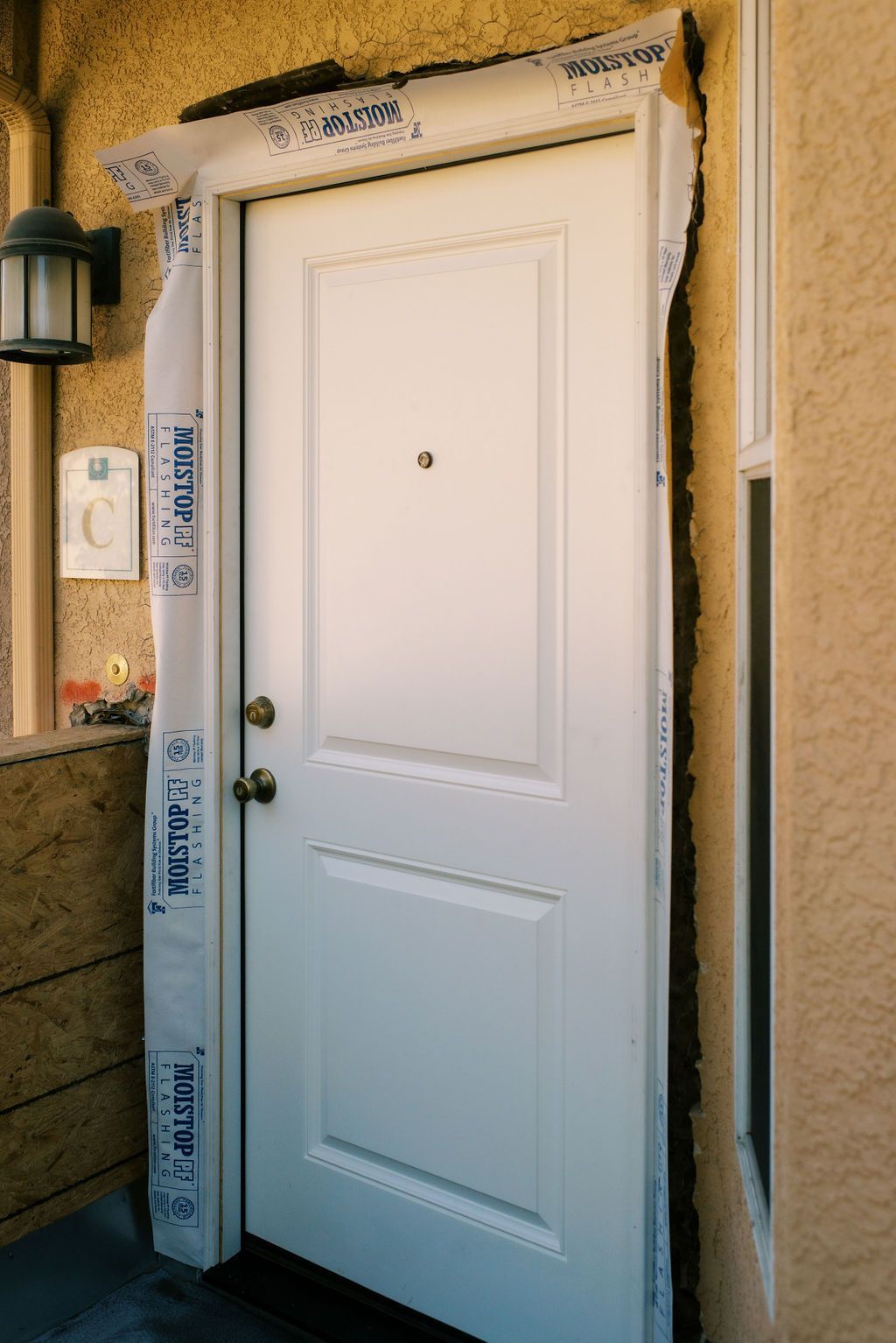 A white door is sitting on the side of a building.