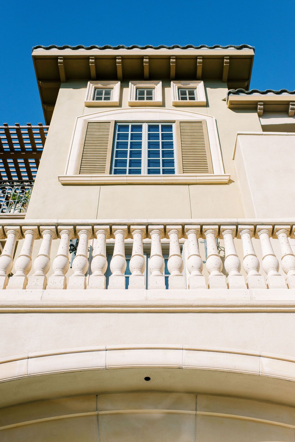 A white building with a balcony and a blue sky in the background.