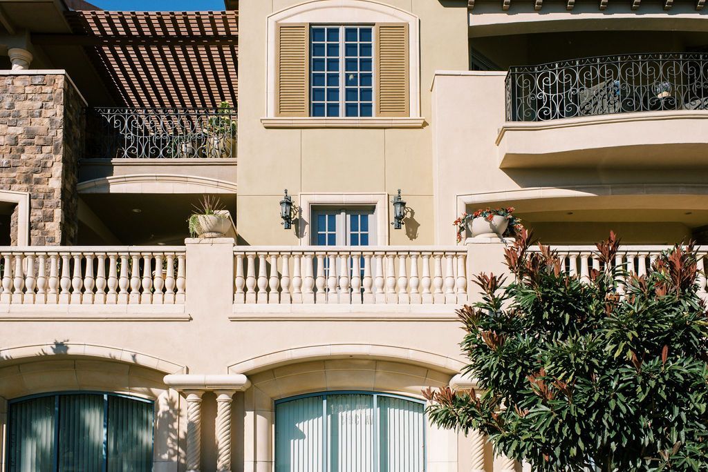 A large house with a balcony and a tree in front of it.