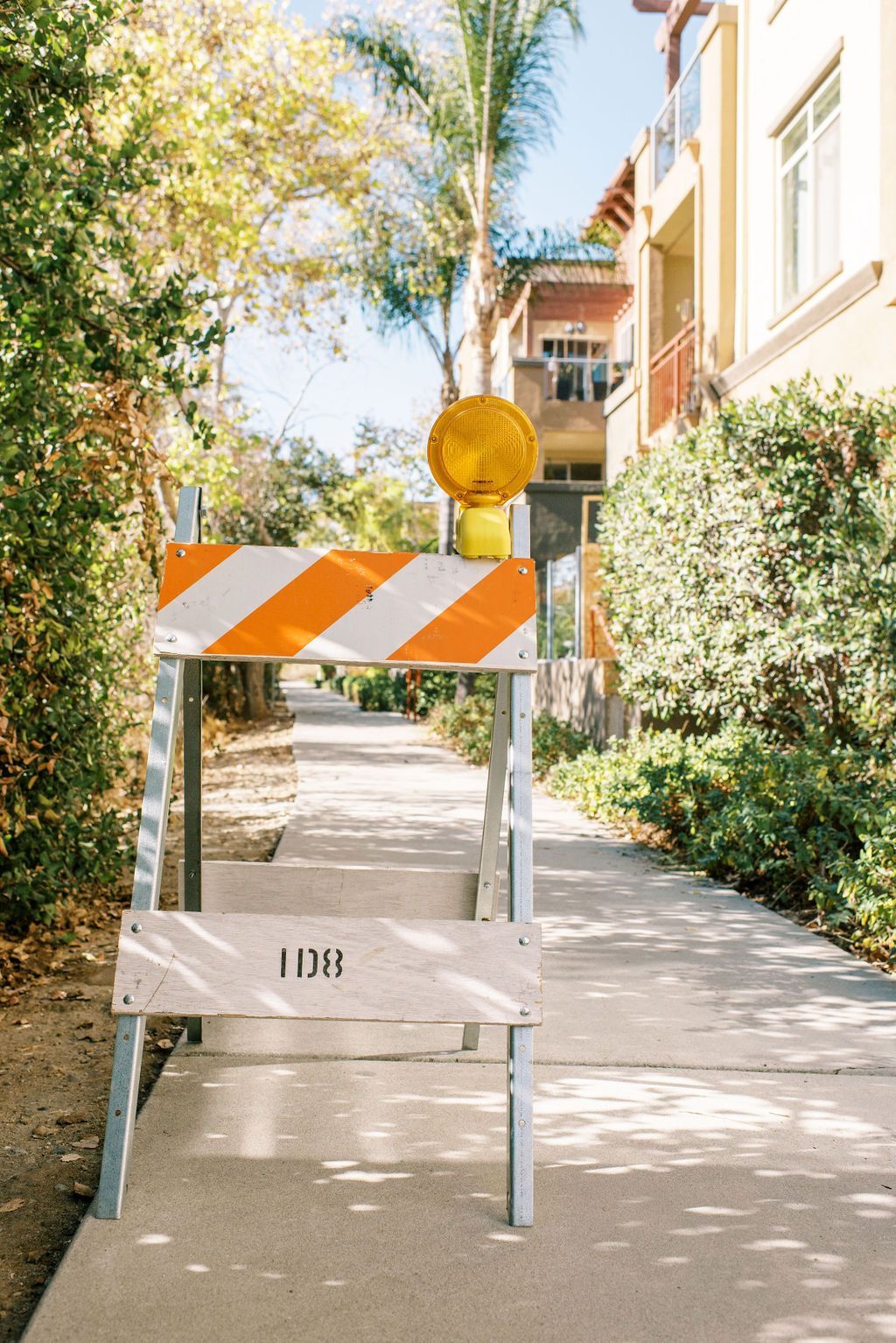 A construction barrier is sitting on the side of a sidewalk.