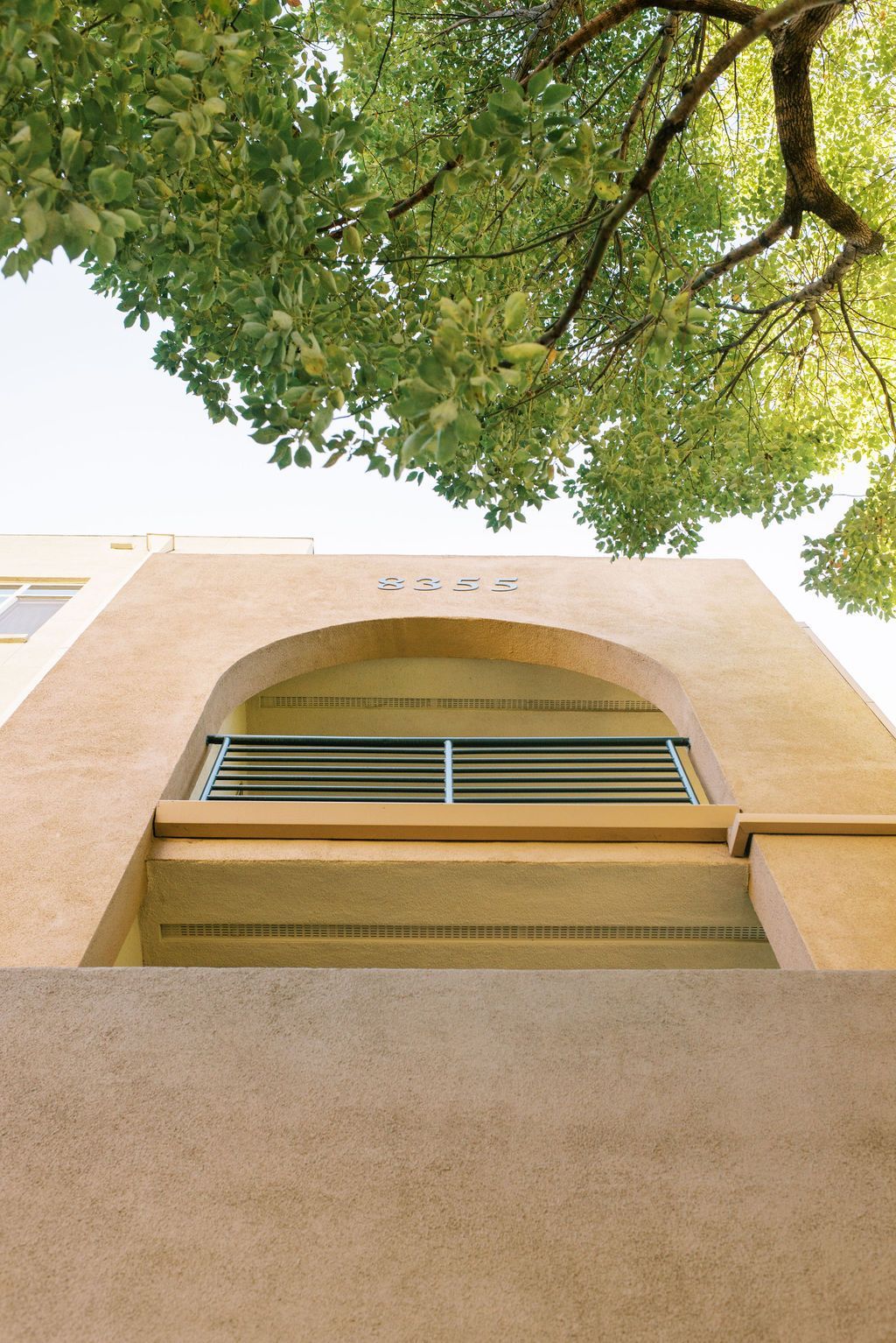 Looking up at a building with a tree in the background.