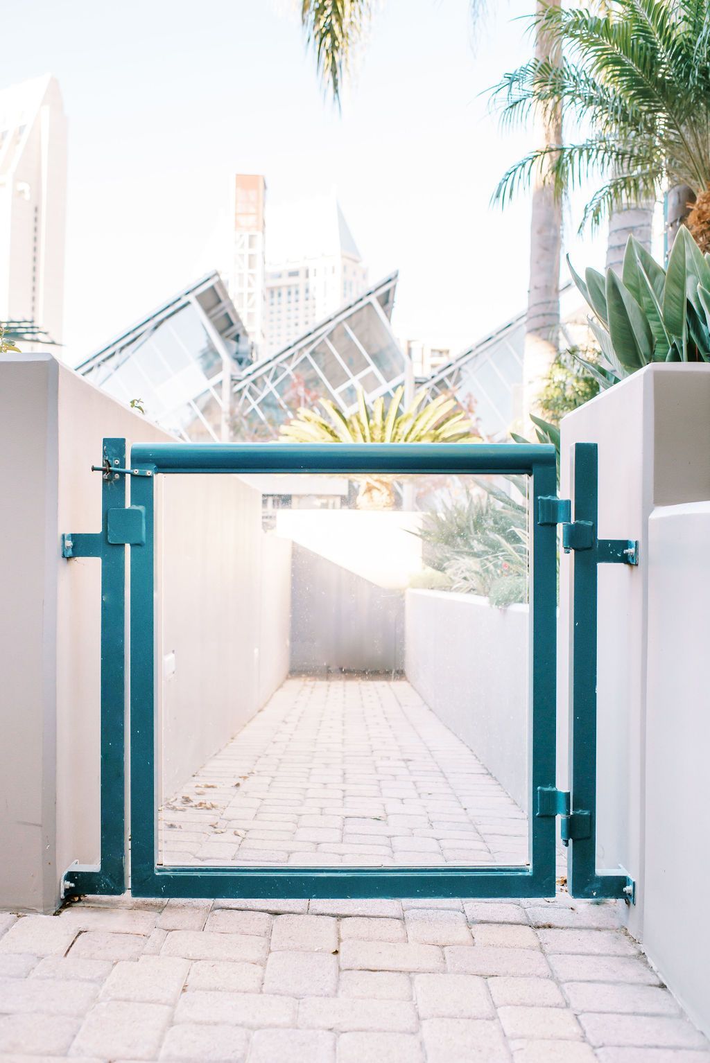A blue gate is leading to a brick walkway.