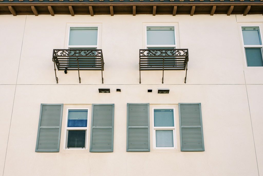A white building with green shutters on the windows