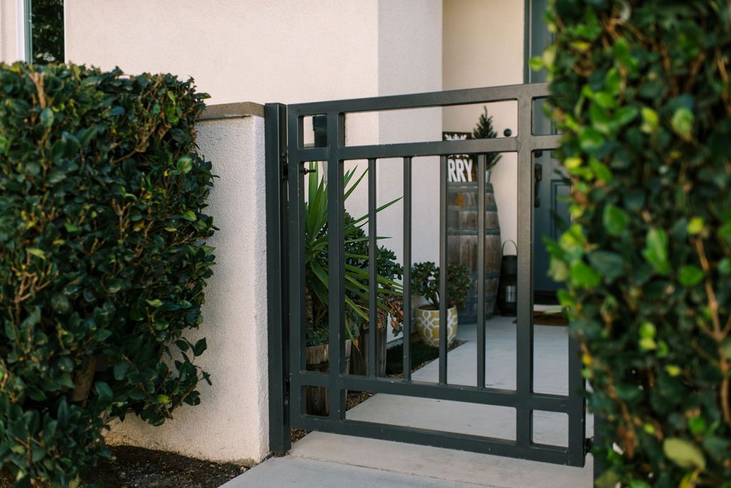 A black gate is leading to a white house.