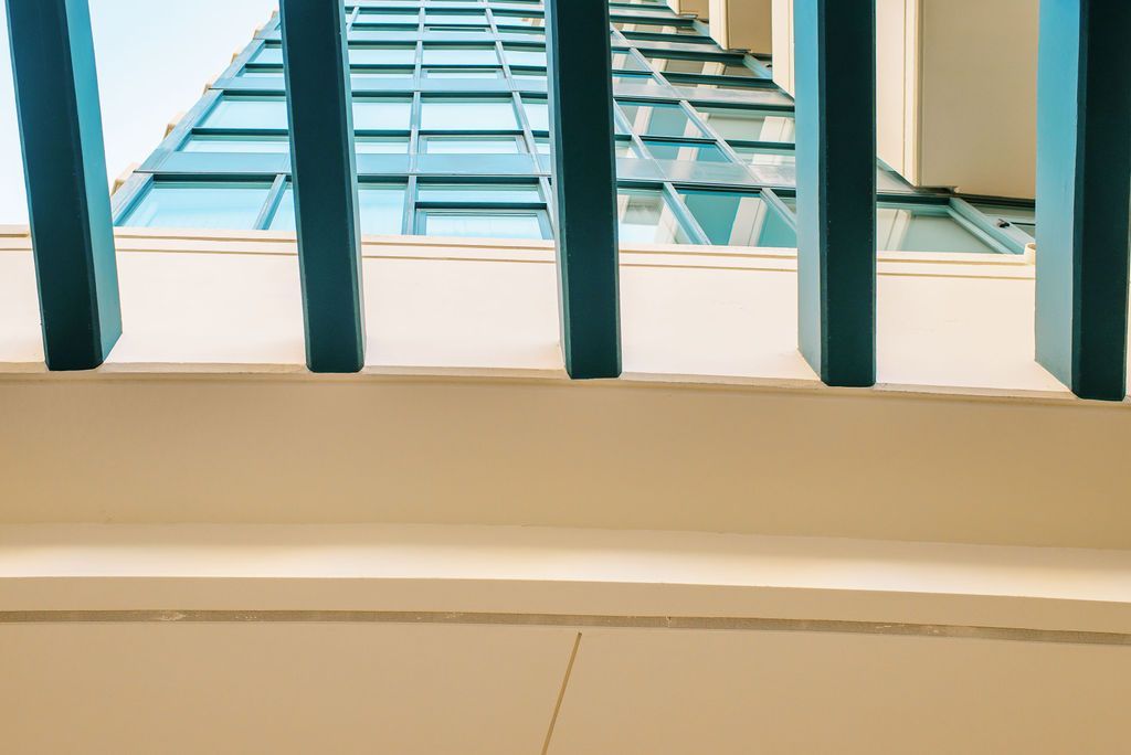 A view of a building through a window with a railing.