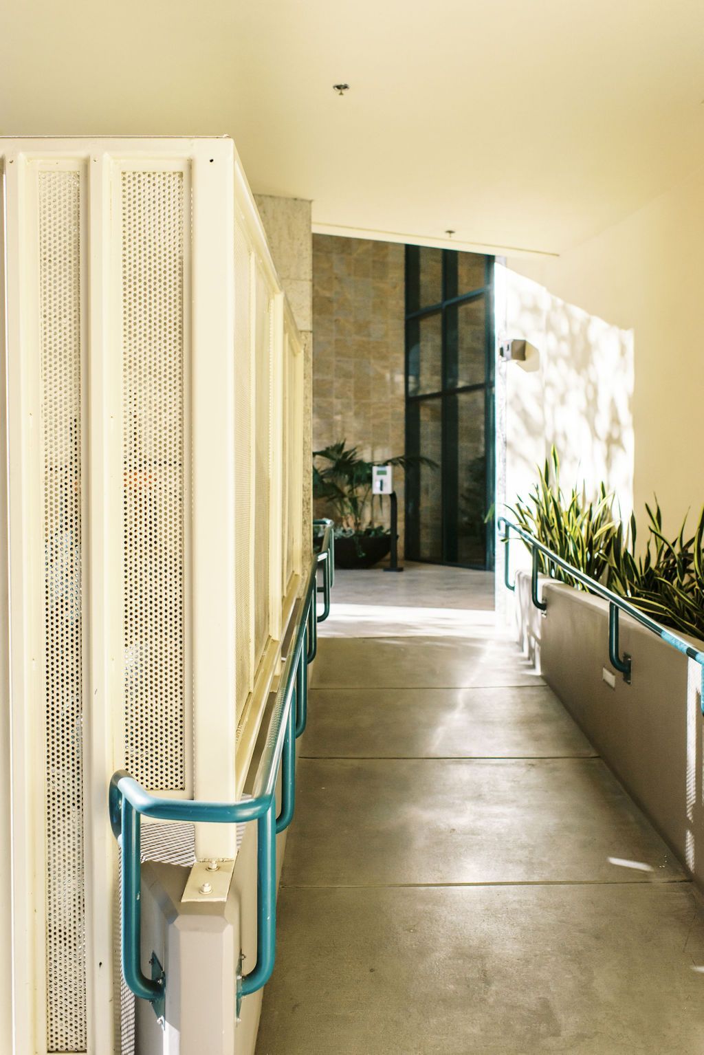 A hallway with a blue railing leading to an elevator