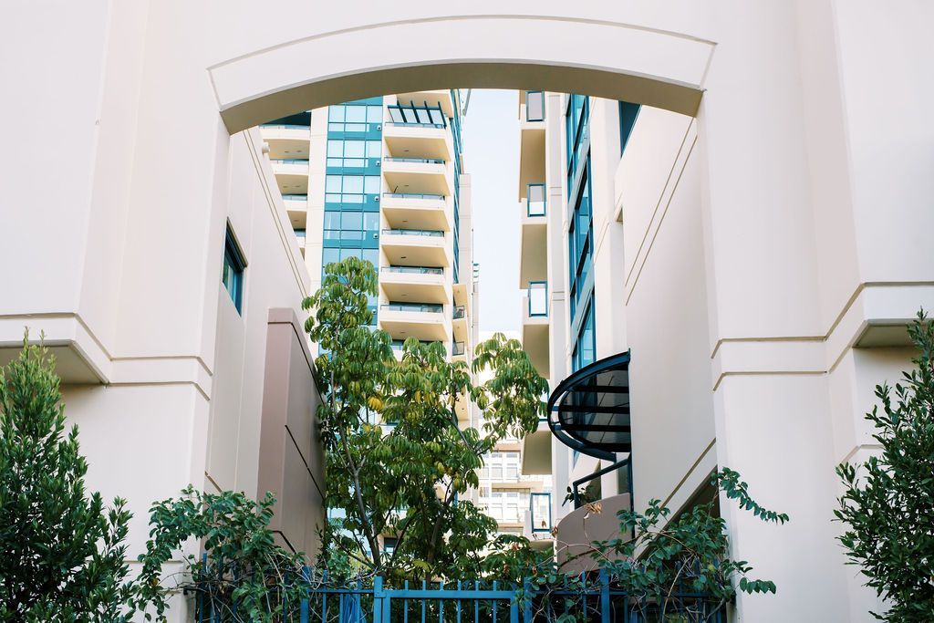 A view of a building through an archway surrounded by trees.
