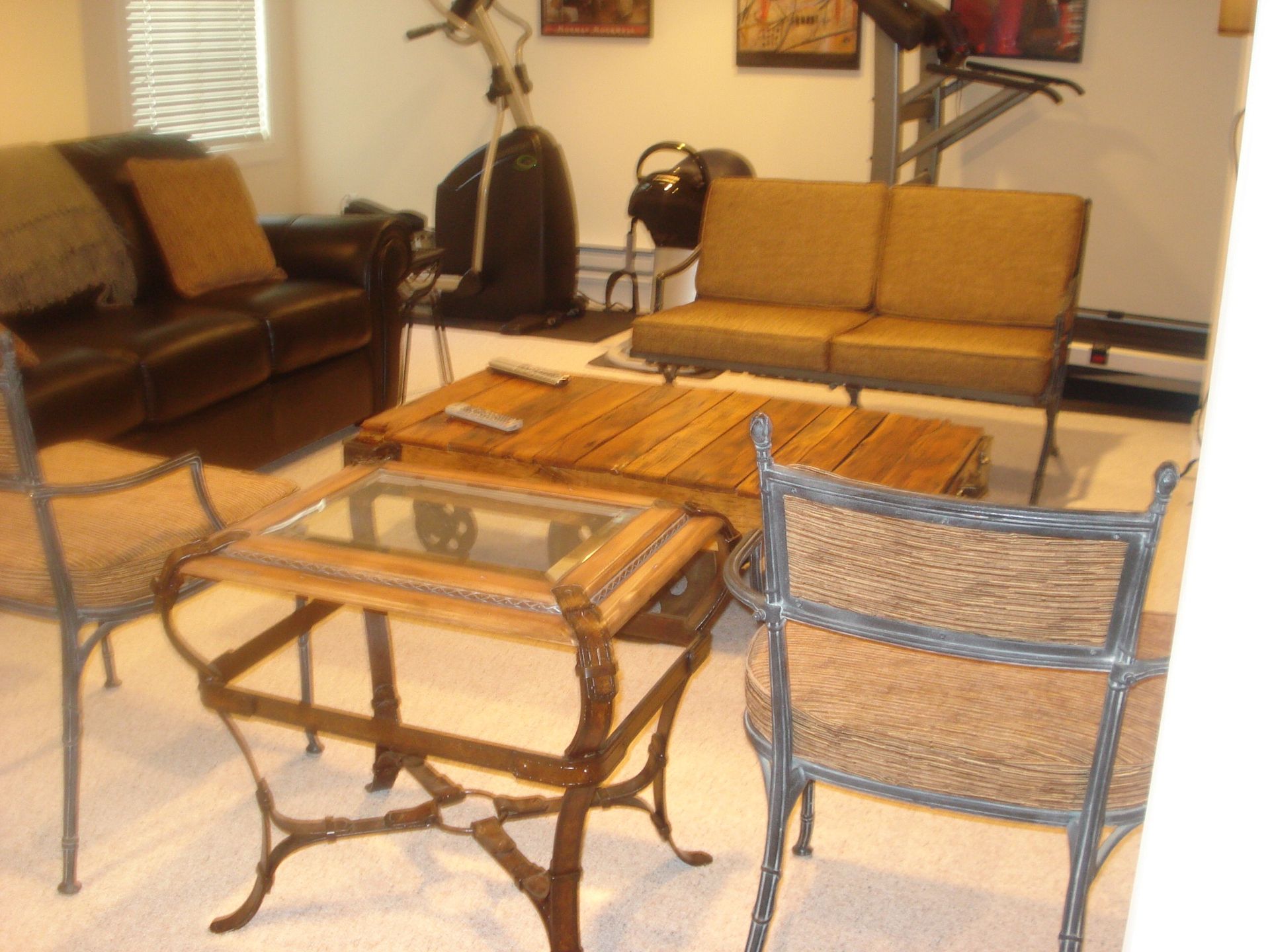 Living room with sofa, coffee tables, and chairs. Exercise equipment visible in the background.