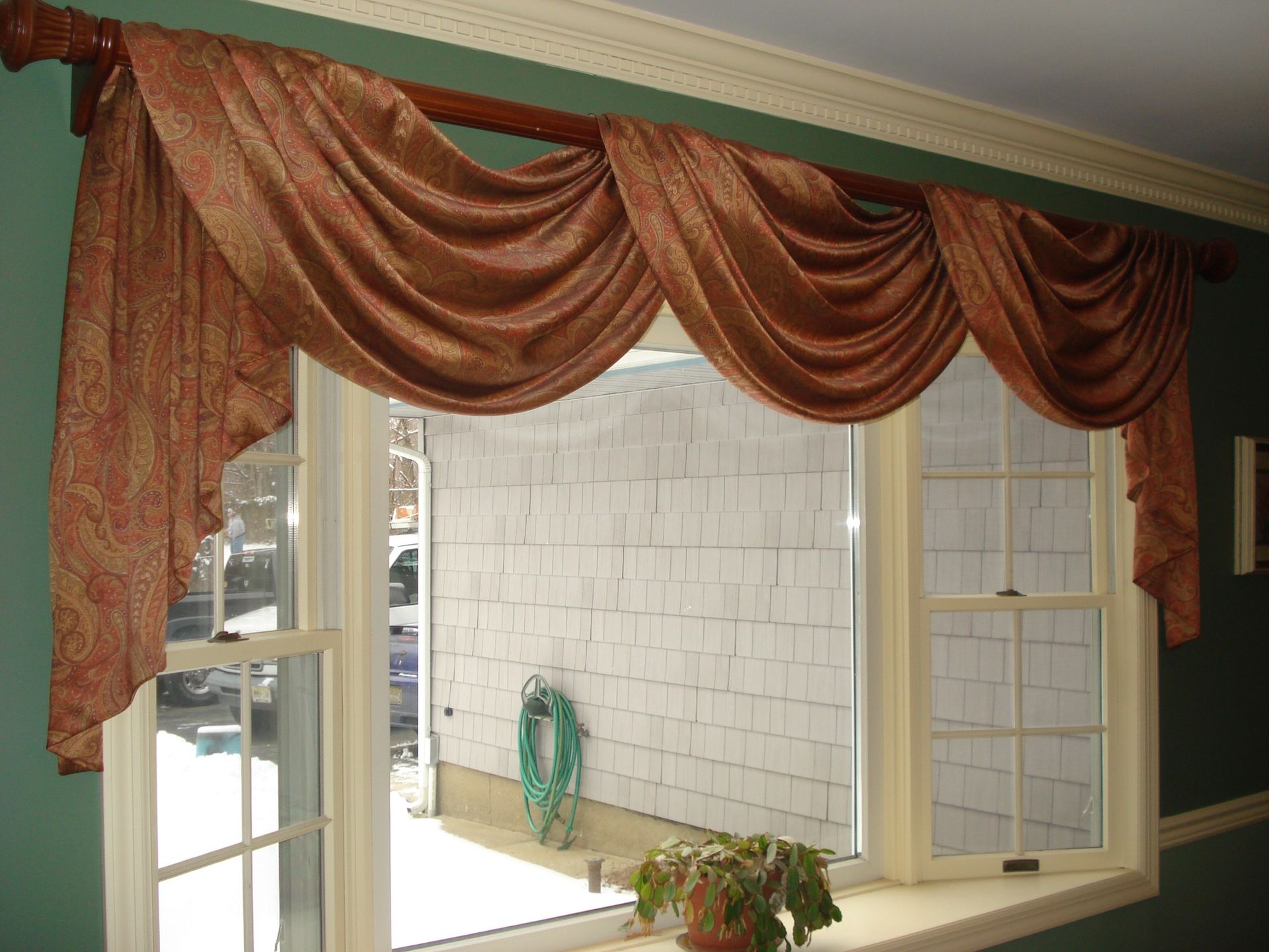 Brown patterned window valance over a double-hung window, interior setting.