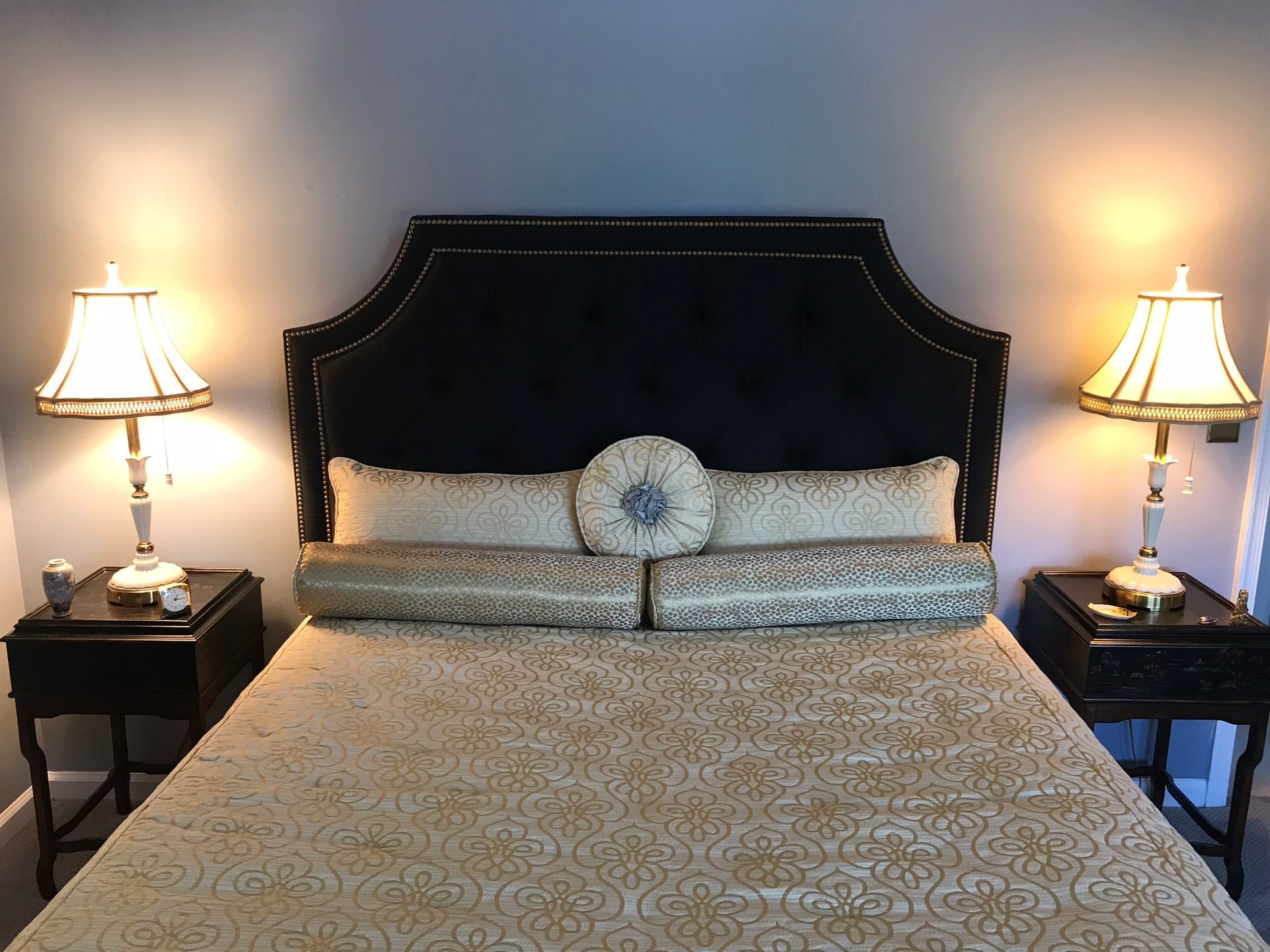 Bedroom with gold bedspread, black headboard, nightstands, and lamps.