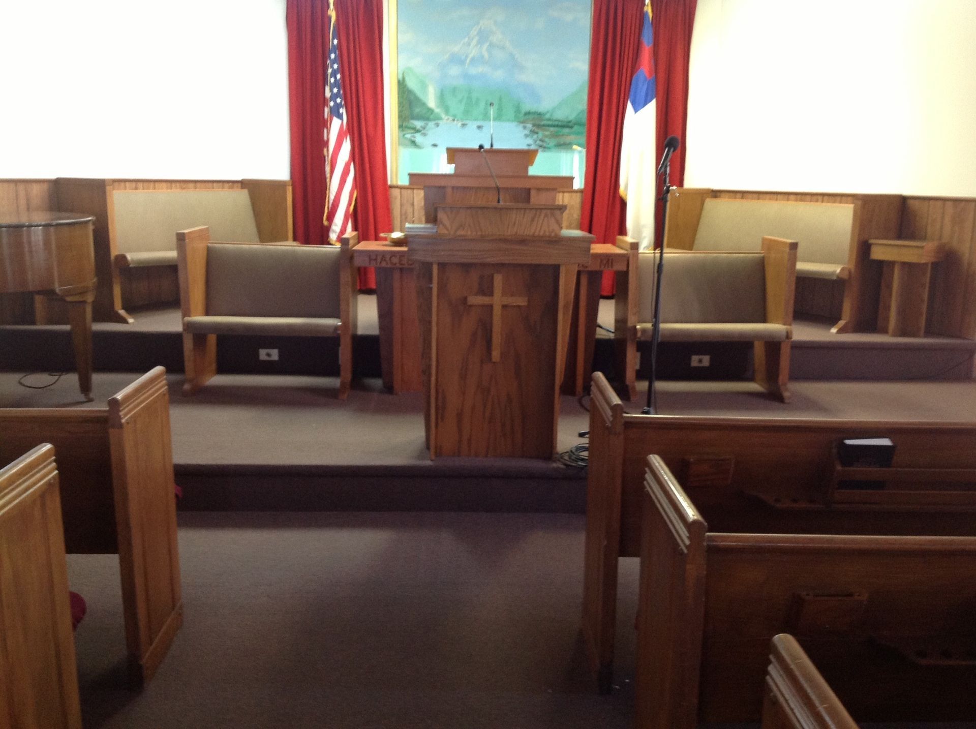Interior of a church sanctuary with wooden pews, altar, pulpit, and flags.