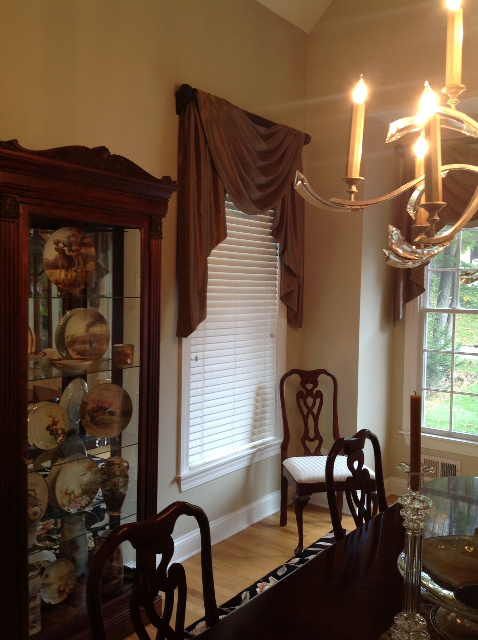 Dining room with ornate furniture, brown drapes, a chandelier, and a display cabinet with china.