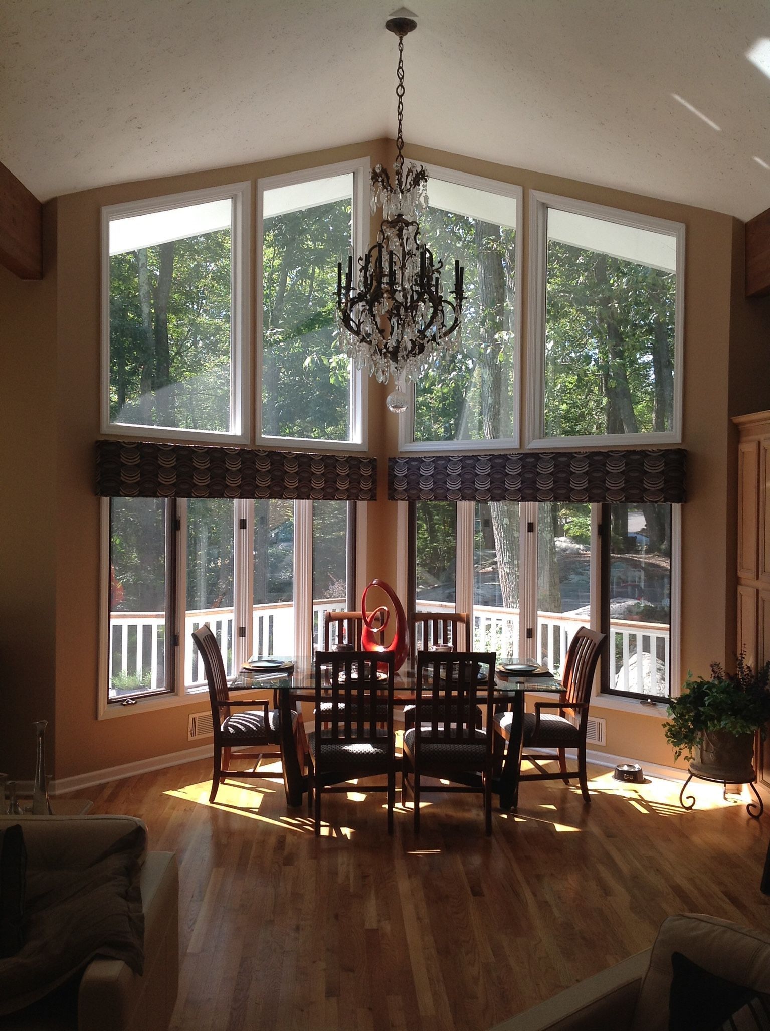 Dining room with tall windows, chandelier, table, chairs, and sunlight.